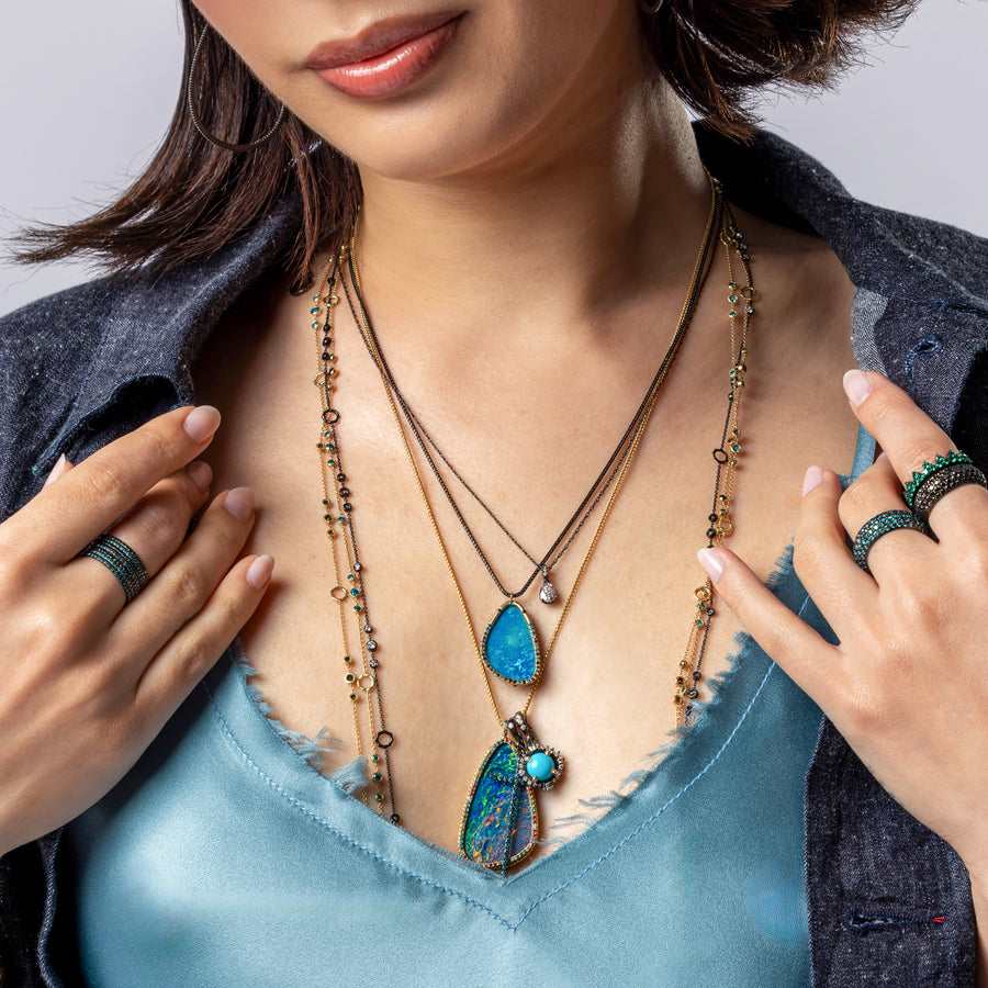 Closeup on-model jewelry, apparel collection Rhythm and Blues in Australian opals, diamonds, blue diamonds, and other gemstones set in black gold, yellow gold; 323-404-2959 for shop help