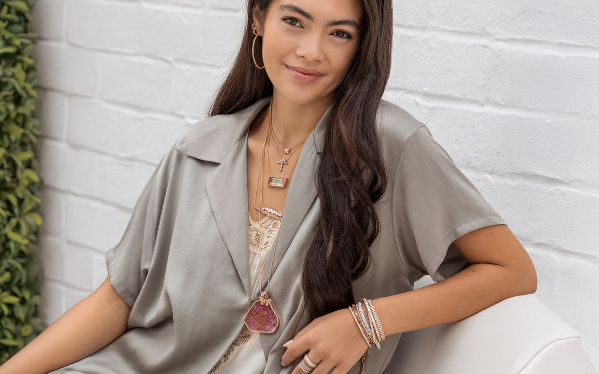 Shop the look Northern Lights, a rose gold diamond, champagne diamond, pink and banded tourmalines jewely and apparel collection, here on a lovely woman on a linen outdoor sofa; shop help at 750-978-9297