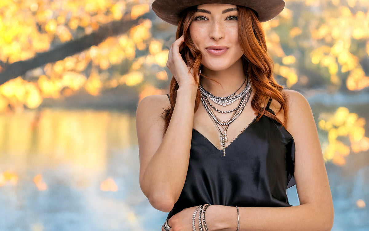 Black gold, rose gold, white gold stylish diamond jewelry and apparel collection De-Lovely on a happy redhead standing by a lake<span class='visuallyhidden'>; shop help at 760-978-9297.</span>