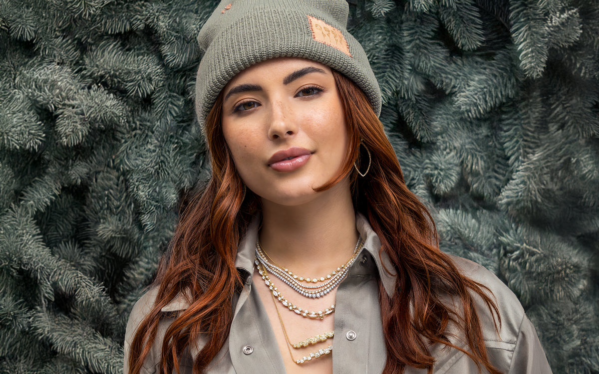 Swoop, a Dominique Cohen diamond + yellow diamond jewelry + apparel collection worn by a lovely redhead wearing a sage-hued limited edition designer beanie and silk shirt; shop help at 760-978-9297