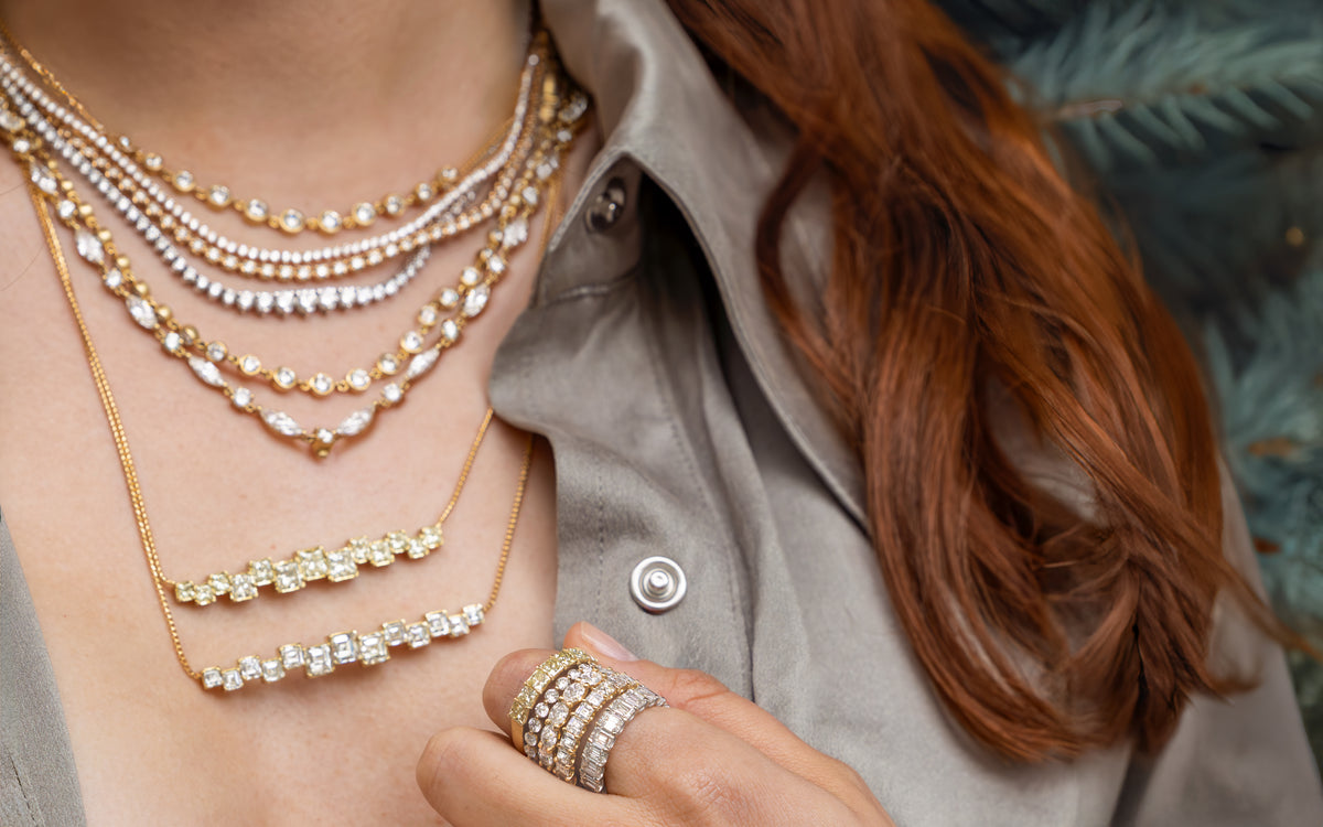 Swoop, a Dominique Cohen diamond + yellow diamond jewelry + apparel collection worn by a lovely redhead wearing a sage-hued limited edition designer beanie and silk shirt; shop help at 760-978-9297